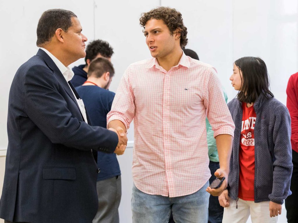 Student shaking the hand of a an alum at a networking event