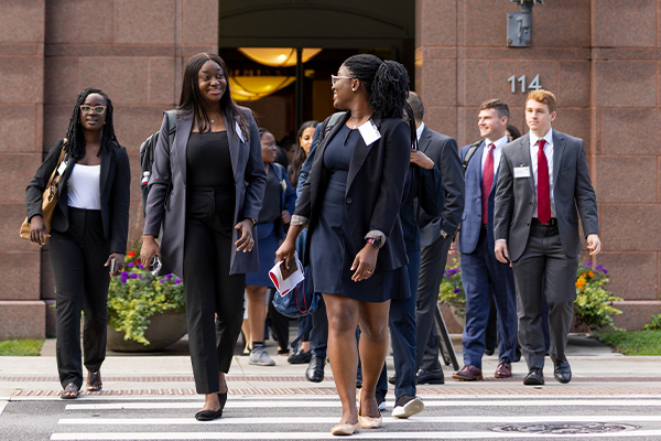 Students in business attire walking across a road.