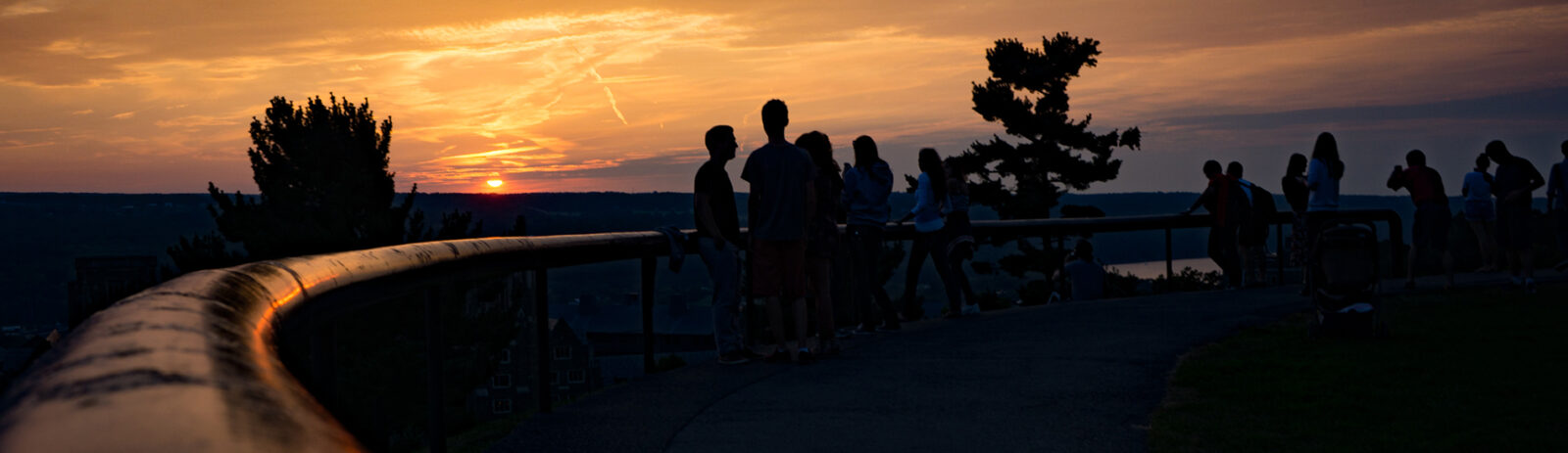 A landscape image of students at sunset talking in a group.